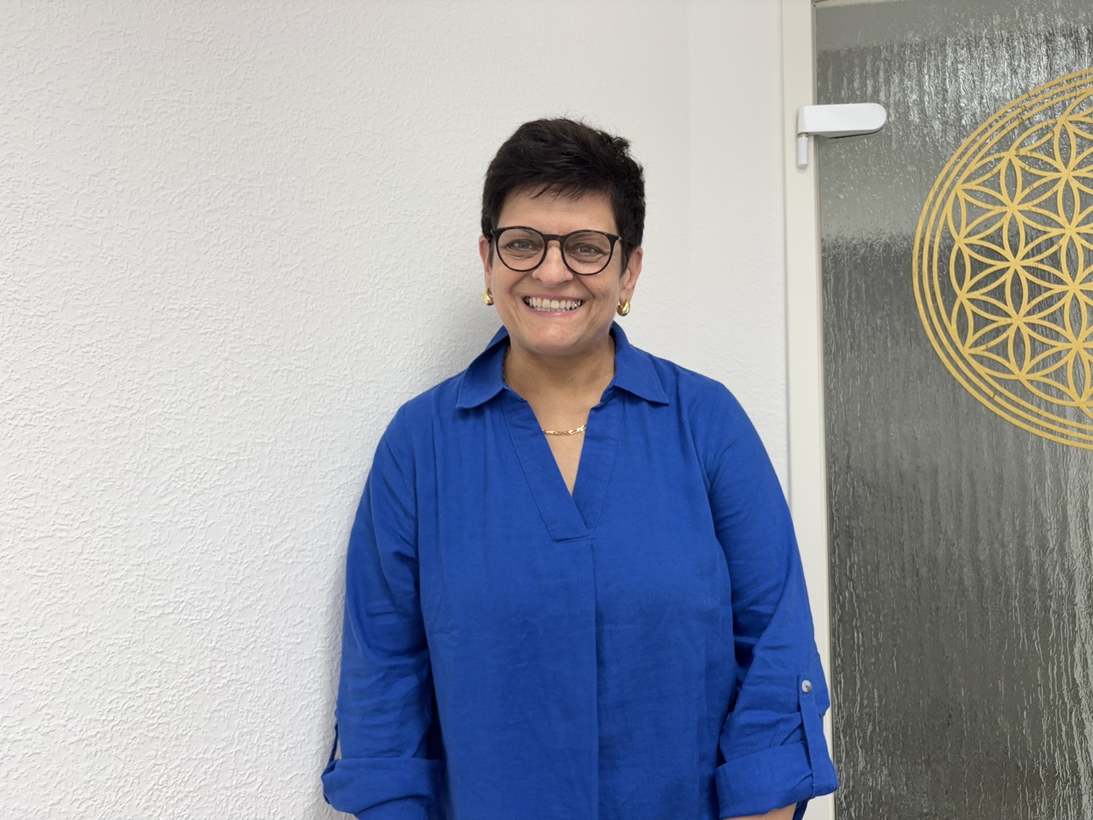 Dr. Dagmar Lauer in ihrer Praxis vor einer Blume des Lebens.